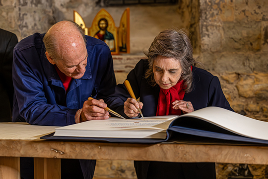 Elaine Culver (right) burnishes the gift of an Apostles Edition of The Saint John’s Bible with the help of Donald Jackson, the creator and artistic director of The Saint John’s Bible (left) at Lambeth Palace. 