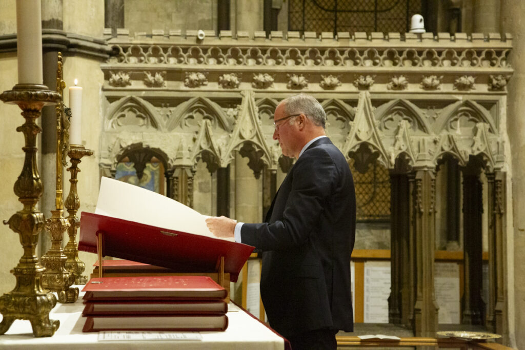 President Brian J. Bruess, Ph.D., of Saint John’s University and the College of St. Benedict, places one volume of the Heritage Edition on its stand during the blessing and dedication of this Heritage Edition at Canterbury Cathedral. November 2023.